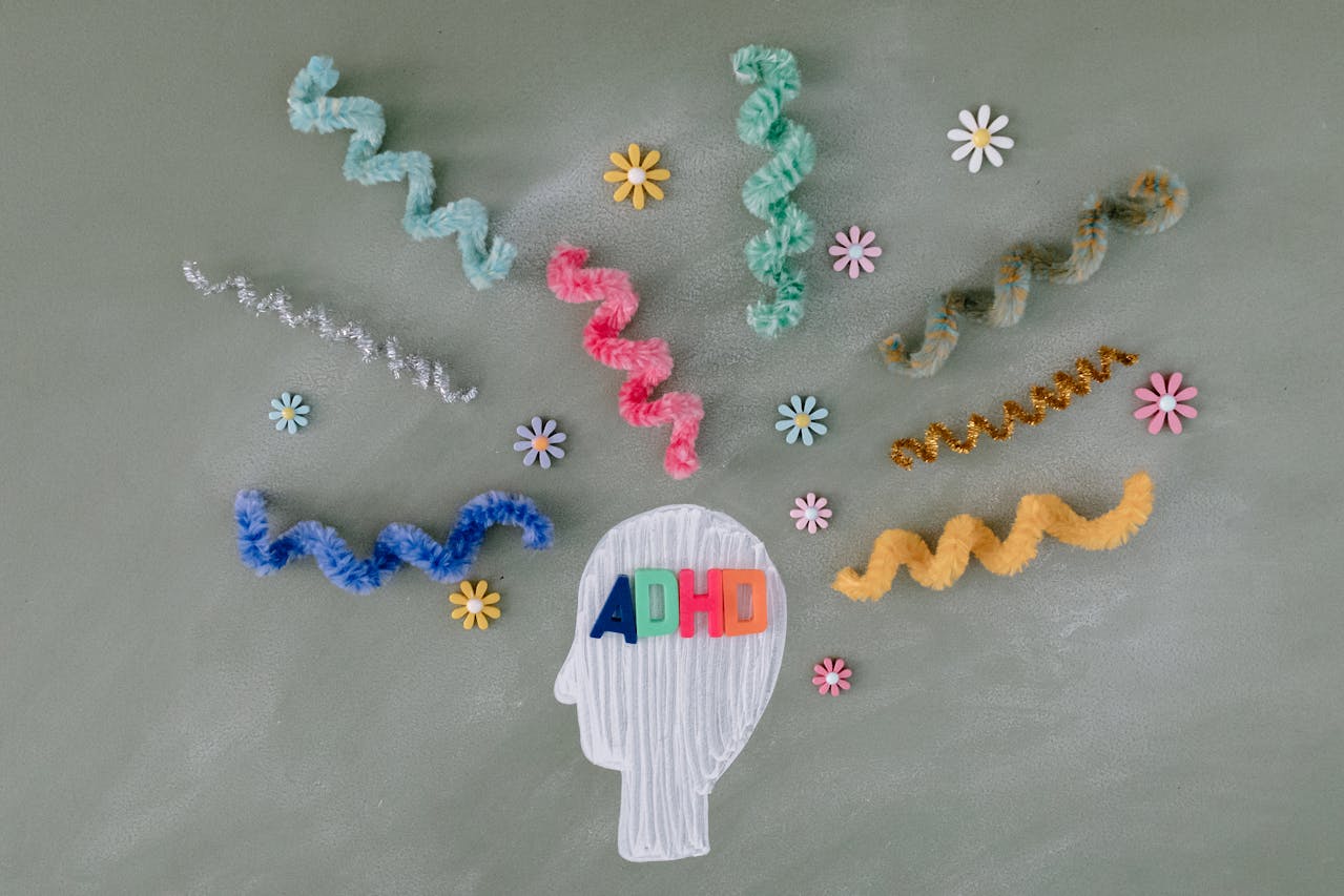 Colorful pipe cleaners and flowers surround a head outline with "ADHD" letters inside.
